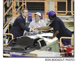 U.S. President George W. Bush shakes hands with Boeing employee Sam Jones as Dan Wagoner looks on